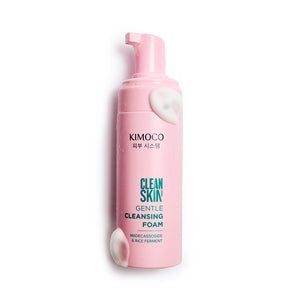 Po środku różowa butelka kosmetyku Kimoco Clean Skin Gentle Cleansing Foam z białą pianką przy pompce i przy dnie, na białym tle.