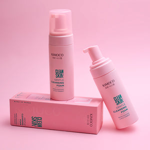 Dwie różowe butelki z pompką kosmetyku Kimoco Clean Skin Gentle Cleansing Foam stojące na różowym pudełku, na różowym tle.