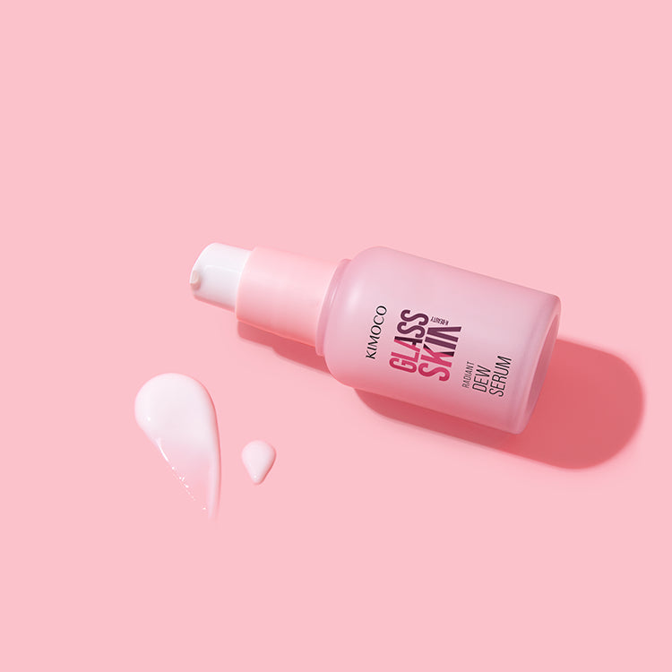 Różowa butelka z pompką kosmetyku Kimoco Glass Skin Radiant Dew Serum, na jasnoszarym tle.