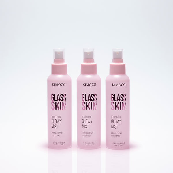 Trzy identyczne różowe butelki z rozpylaczem kosmetyku Kimoco Glass Skin Refreshing Glowy Mist ustawione obok siebie, na jasnoszarym tle
