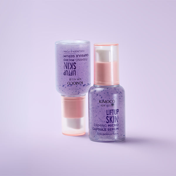 Z prawej stojąca butelka "Kimoco Lift-Up Skin Firming Micro Capsule Serum" z fioletowym serum, z lewej taka sama butelka odwrócona do góry nogami, na jasnoróżowym tle.