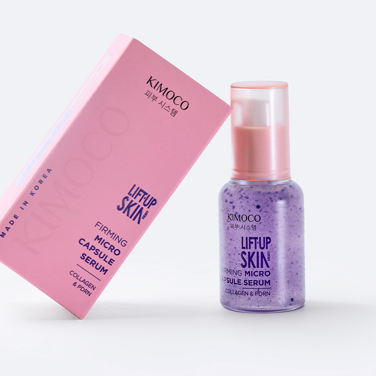 Przezroczysta butelka z fioletowym serum "Kimoco Lift-Up Skin Firming Micro Capsule Serum" i widocznymi drobnymi kapsułkami wewnątrz, na białym tle.