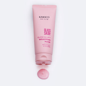 Różowa tubka kosmetyku Kimoco Glass Skin Glow & Lift Wrapping Mask z ekstraktem ryżowym i kolagenem, poniżej niewielka kropla wyciśniętego produktu, na białym tle.