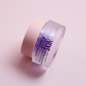 Zamknięty fioletowy słoiczek kosmetyku Kimoco Lift-Up Skin Skin Boosting Capsule Face Cream z kolagenem i PDRN, leżący na boku, na jasnoróżowym tle.