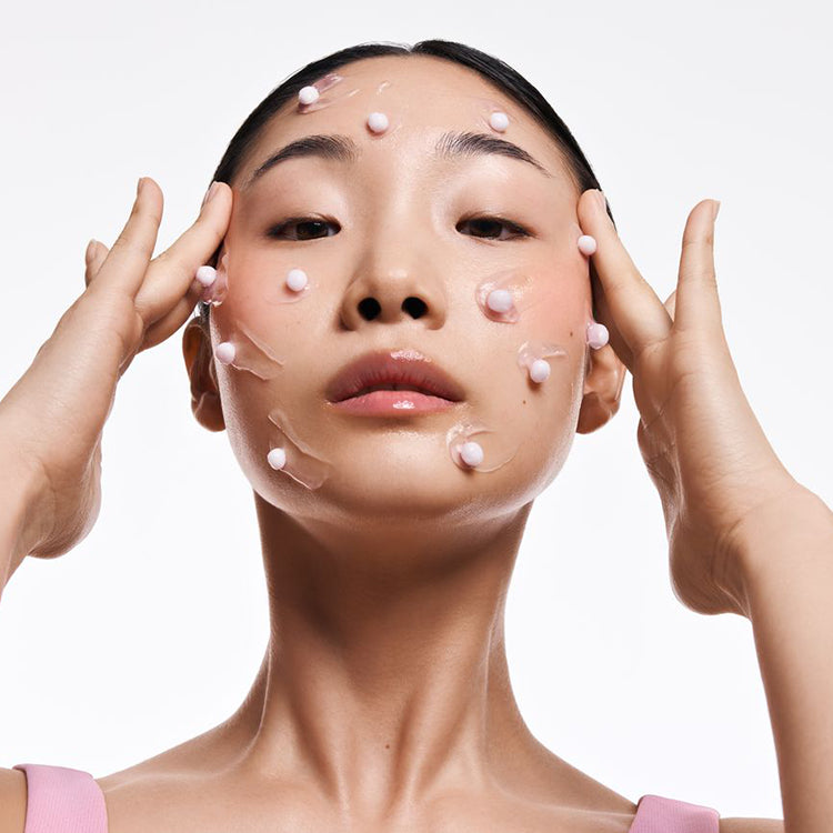 Otwarty słoiczek Kimoco Lift-Up Skin Capsule Face Cream z fioletowymi kapsułkami, z lewej różowa zakrętka, na białym tle.